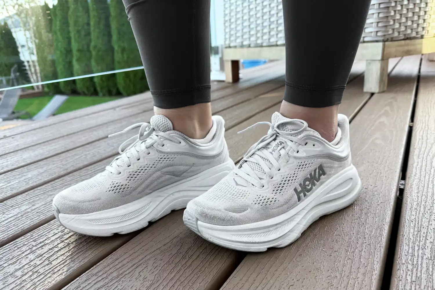 Person wearing Hoka Bondi 9 shoes on a wooden deck