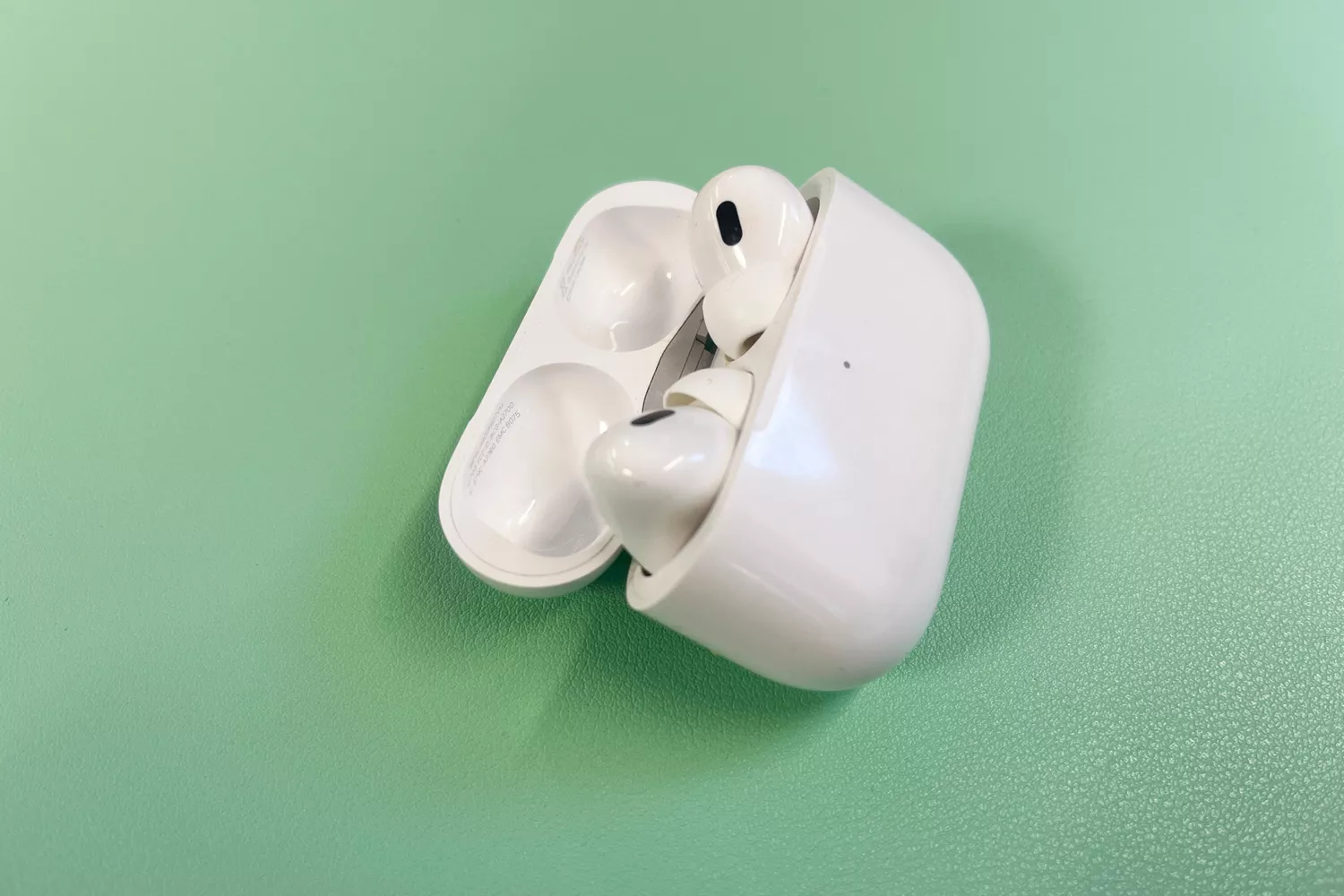 Apple AirPods Pro (2nd Generation) in charging case on a green surface