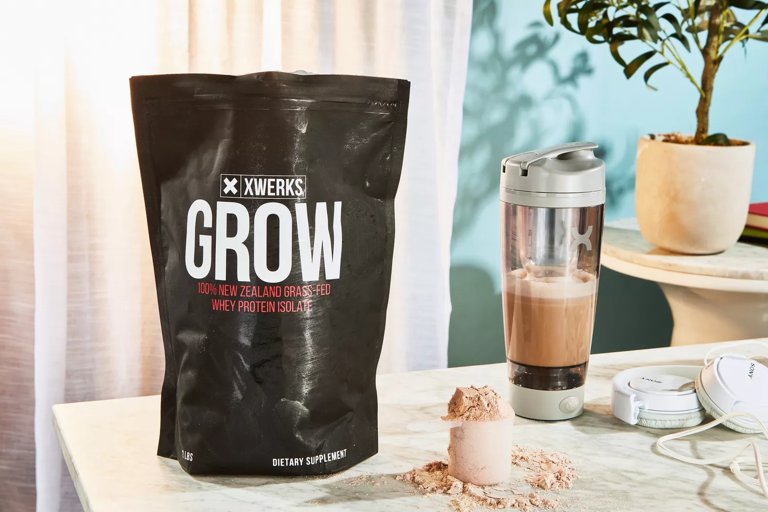Xwerks Grow 100% New Zealand Grass-Fed Whey Protein Isolate next to a scoop and shaker bottle