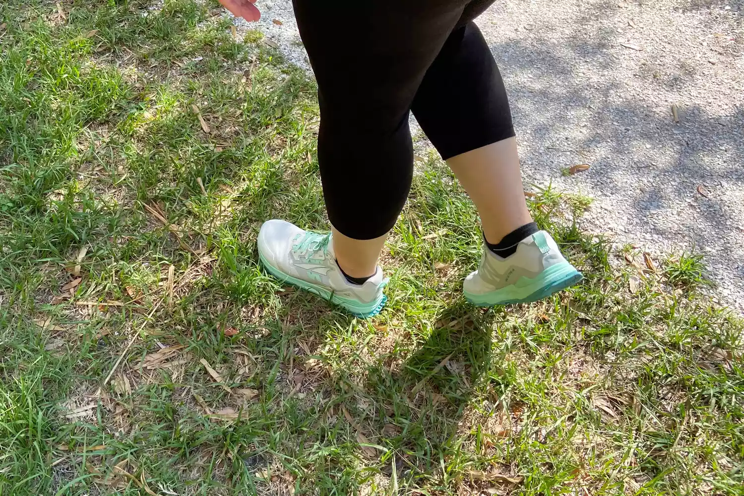 A person walking on grass while wearing Altra Women's Lone Peak 7 Trail Running Shoes