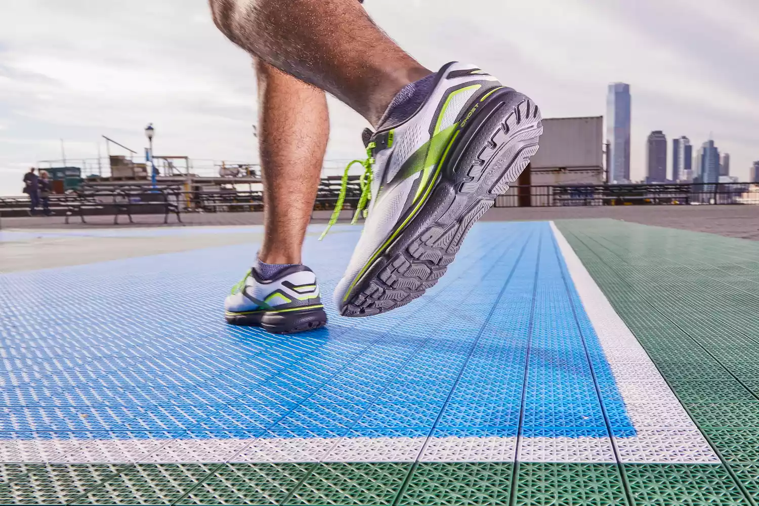 Close-up of a person wearing Brooks Men's Ghost 15 Running Shoes on an outdoor track
